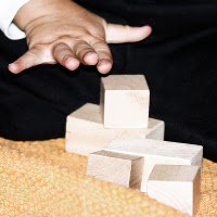 la mano di un bambino che gioca con i cubi di legno